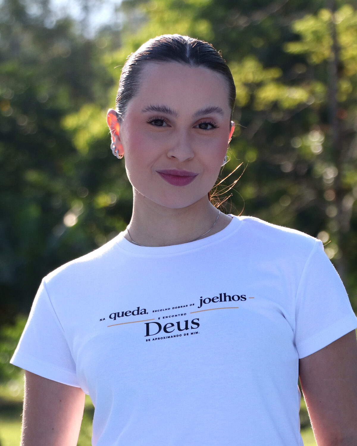 Modelo vestindo camiseta branca Zoe163 com estampa Na queda, escolho dobrar os joelhos
